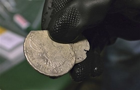 A member of Spain's Culture Ministry's technical crew displays two of the 594,000 coins and other artifacts found in the Nuestra Senora de las Mercedes, a Spanish galleon sunk by British warships in the Atlantic in 1804.